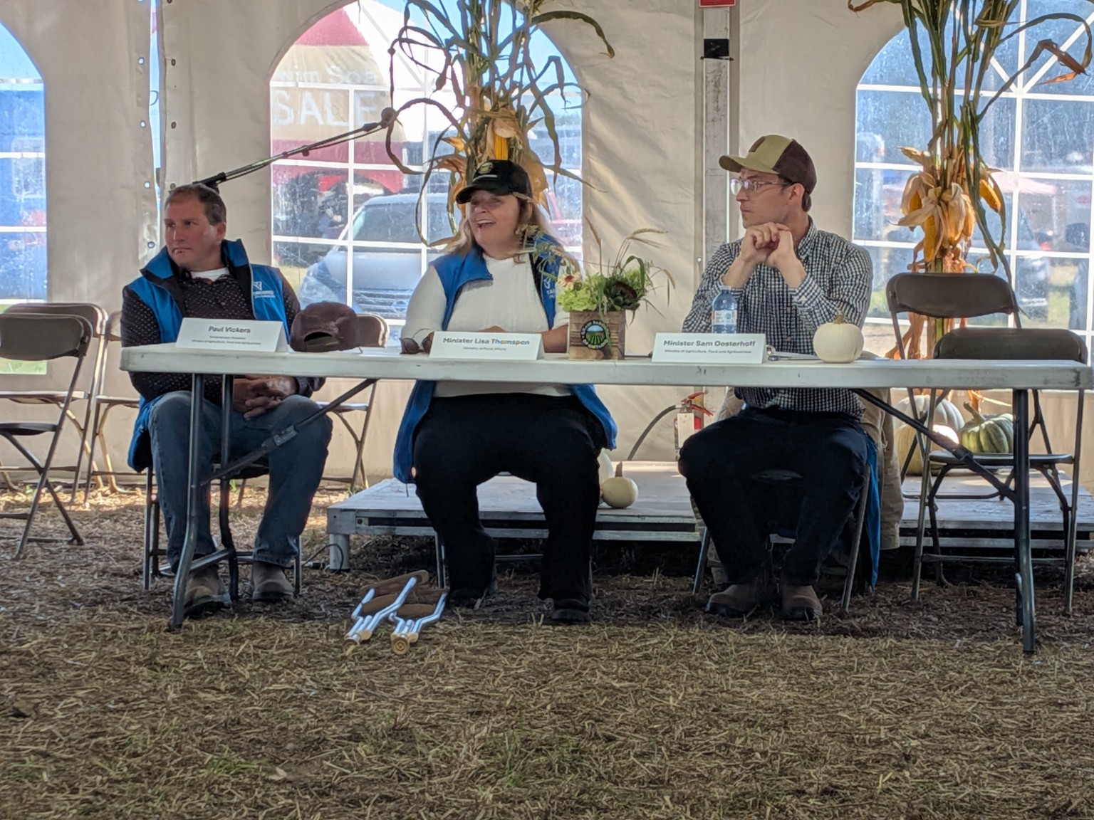 The commodity roundtable panel seated at the International Plowing Match. Nameplates read Paul Vickers, Minister Lisa Thompson and Minister Sam Oosterhoff.